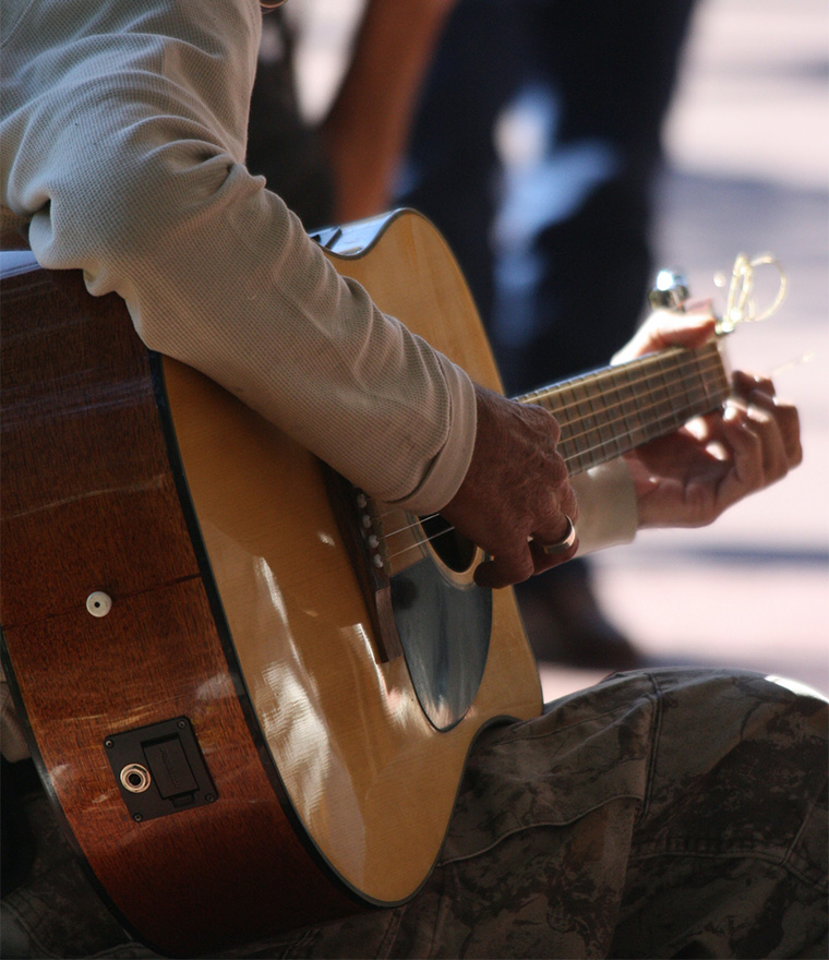 Person busking on street with guitar.
