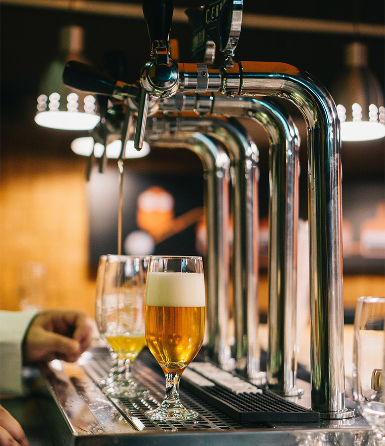 People pouring beers from tap at brewery.