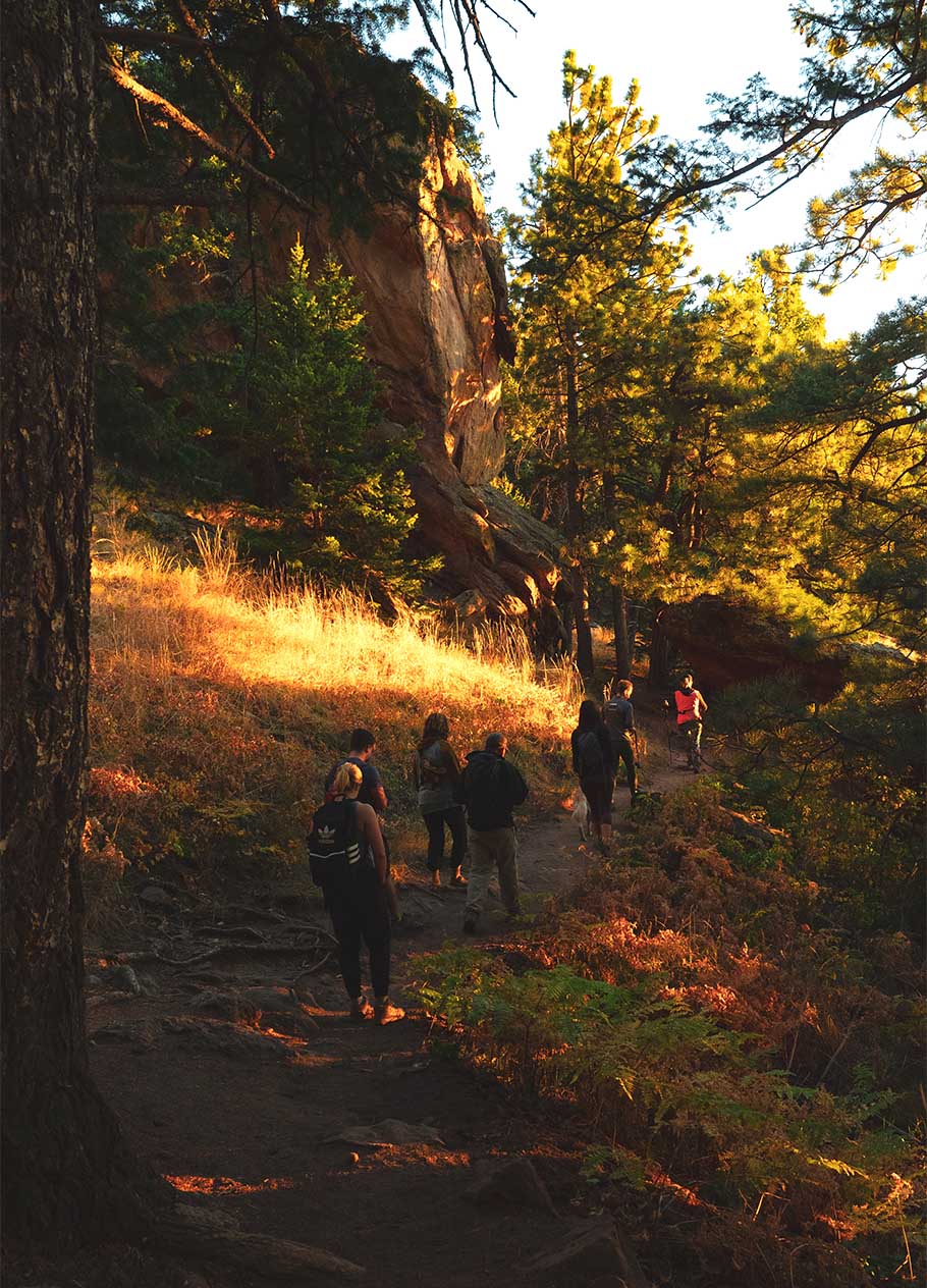 People walking in the shade along a mountain trail in Boulder.
