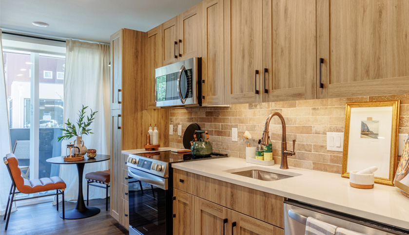 Modern wood finished kitchen in apartment home with large window and kitchen table